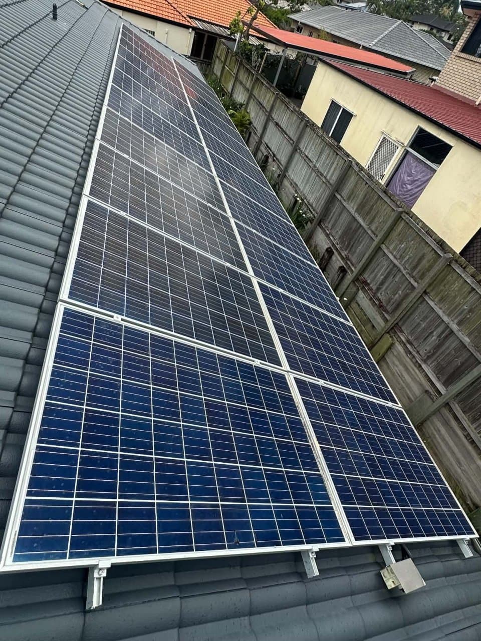 A solar array on a tiled roof before the work, with bare roof tiles along the edge of the panels