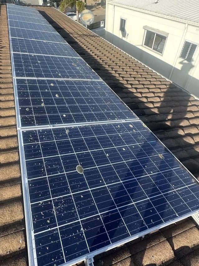 Solar panels on a tiled roof marked with bird droppings and dirt before cleaning